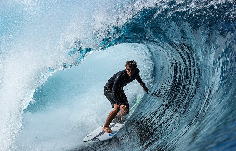 A surfer rides inside the barrel of a wave